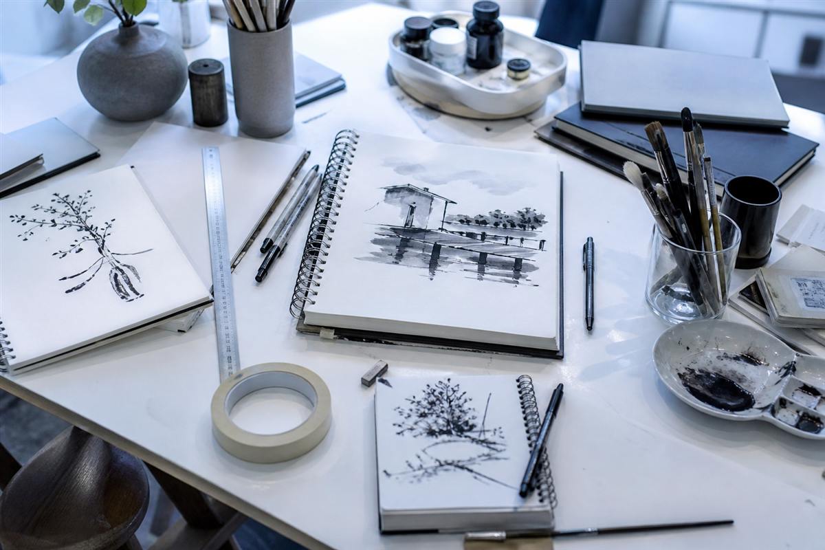 Sketchbooks, pens, and brushes on a studio table